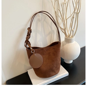 Détail du sac seau mat marron foncé avec bandoulière à nœud tressé et porte-monnaie rond