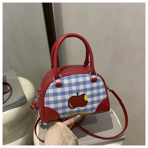 Detail of red leather Boston bag with blue plaid fabric and cute apple patch design