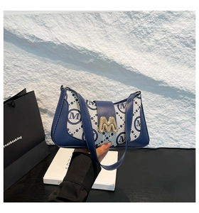 Detail of blue monogram jacquard shoulder bag with golden metallic M buckle closure