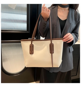 Detail of cream tote bag with brown trim and long shoulder straps for daily use