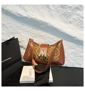 Close-up of vintage brown printed baguette bag with golden metal M-shaped buckle