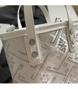 Close-up of jacquard fabric pattern with white leather handles and reinforced metal rivets