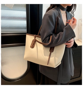 Detailed side view of a large cream tote bag with brown straps worn by a model