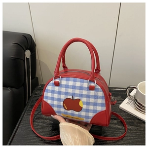 Detail of Boston plaid handbag with apple print and red leather handles in hand