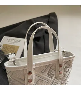 Detail of jacquard bucket bag showing ethnic embroidery and bronze studs on leather handle