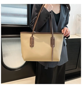 Spacious beige and brown tote bag with smooth leather finish shown with professional attire