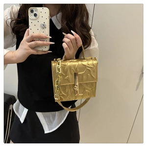 Macro shot of gold embossed leather bag with branch texture and chunky chain strap