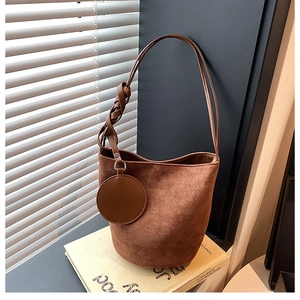 Détail du sac seau vintage en daim marron avec bandoulière nouée et pendentif circulaire