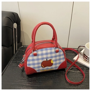 Close-up of blue and white checkered Boston bag with red apple embroidery and leather handles