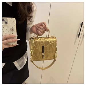 Detailed view of golden square crossbody bag with metallic pleats and chunky chain