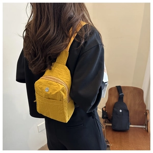 Close-up of yellow textured nylon mini crossbody bag with metallic logo detail