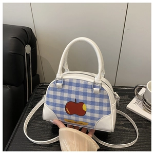 Detail view of blue checkered canvas bowling bag with red apple print and white leather handles