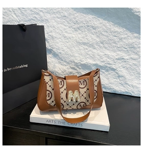 Detail of vintage patterned baguette bag featuring gold M hardware and leather trim