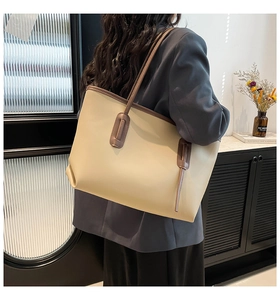 Large beige tote bag with brown trim shown from side-back view for office work commute