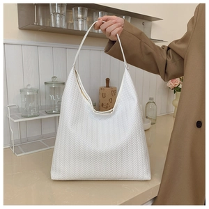 Detail of white woven tote bag with handle shown in a modern minimalist kitchen setting