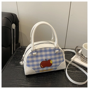 Detail of blue and white checkered handbag featuring a red apple print and PU leather trim