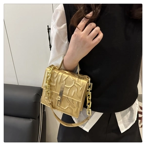 Macro shot of gold structured handbag featuring 3D embossed texture and chunky chain strap