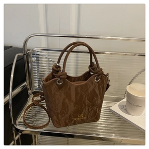 Détail du sac seau marron foncé plissé avec boucles métalliques et bandoulière