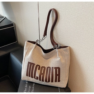 Detail of canvas tote bag with MCADIA lettering and leather shoulder strap handles