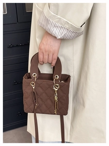 Detail view of brown quilted handbag with gold key pendant and elegant stitching