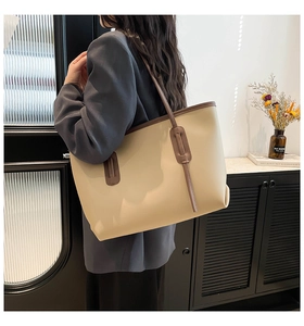 Detail view of large cream leather tote bag with dark brown trim worn by a model