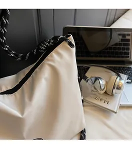 Detailed close-up of white nylon crossbody bag with black and white braided rope strap