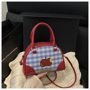 Detail of red boston bag with blue plaid pattern and apple print on fabric