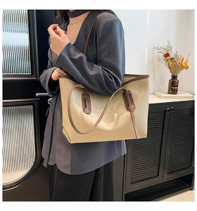 Detail of a large capacity cream tote bag with contrast brown straps for daily commute