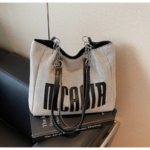 Close-up of canvas tote bag texture with leather straps and metal chain detail