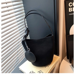 Détail du sac seau en daim noir avec bandoulière nouée et mini porte-monnaie rond attaché