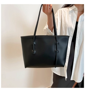 Detail of minimalist black tote bag with unique oval handle attachments and matte texture