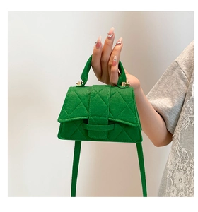 Detail of green felt mini bag featuring diamond quilted texture and gold hardware details