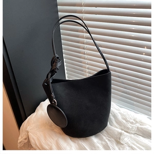 Détail du sac seau en daim noir avec bandoulière nouée élégante et petit charm rond