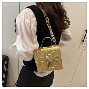 Detail of metallic gold square handbag with embossed texture and chunky chain strap