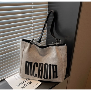 Detailed view of the large canvas tote bag with bold lettering and elegant chain strap