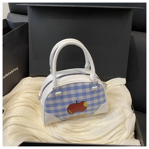 Detail of blue gingham boston bag with red apple print inside a premium gift box