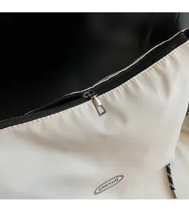 Detail showing smooth metal zipper and black brand logo on minimalist nylon tote bag