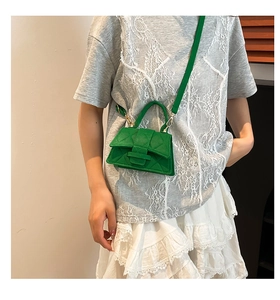 Detail of green quilted mini crossbody bag with golden hardware and hand strap