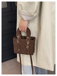 Detailed close-up of brown quilted bag with gold hardware and key-shaped pendant