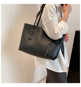 Detail of minimalist black matte leather tote bag showing smooth texture and slim straps