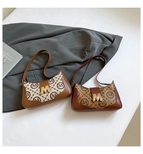 Detail of retro monogram underarm bags in brown and beige with golden M magnetic buckles