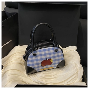 Detail of blue plaid boston bag with red apple print on luxury silk background
