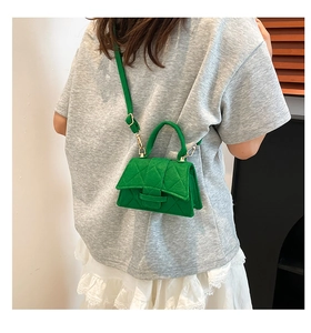 Rear view of a model wearing a emerald green quilted felt crossbody bag with top handle