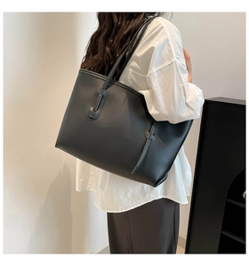 Large black tote bag in matte leather shown on shoulder for daily commute style