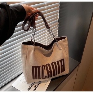 Detail of canvas tote bag with MCADIA lettering and leather metal chain handle