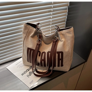 Detail view of the MICMAA letter print on a canvas tote with chain shoulder strap