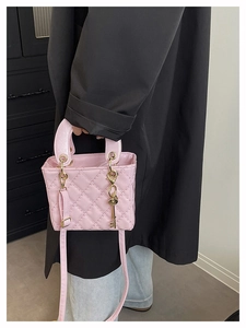 Detailed view of light pink quilted crossbody bag with golden metal ring handles and key charm