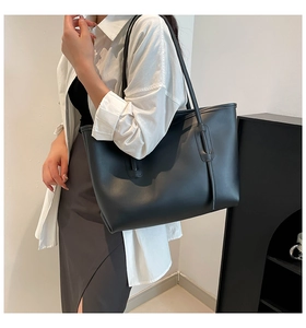 Close-up of minimalist black tote bag with long straps and unique perforated belt detail