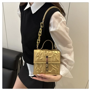 Close-up of golden crossbody bag featuring branch texture and metal chain strap