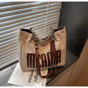 Detail of beige canvas tote bag with brown letter print and metallic chain straps